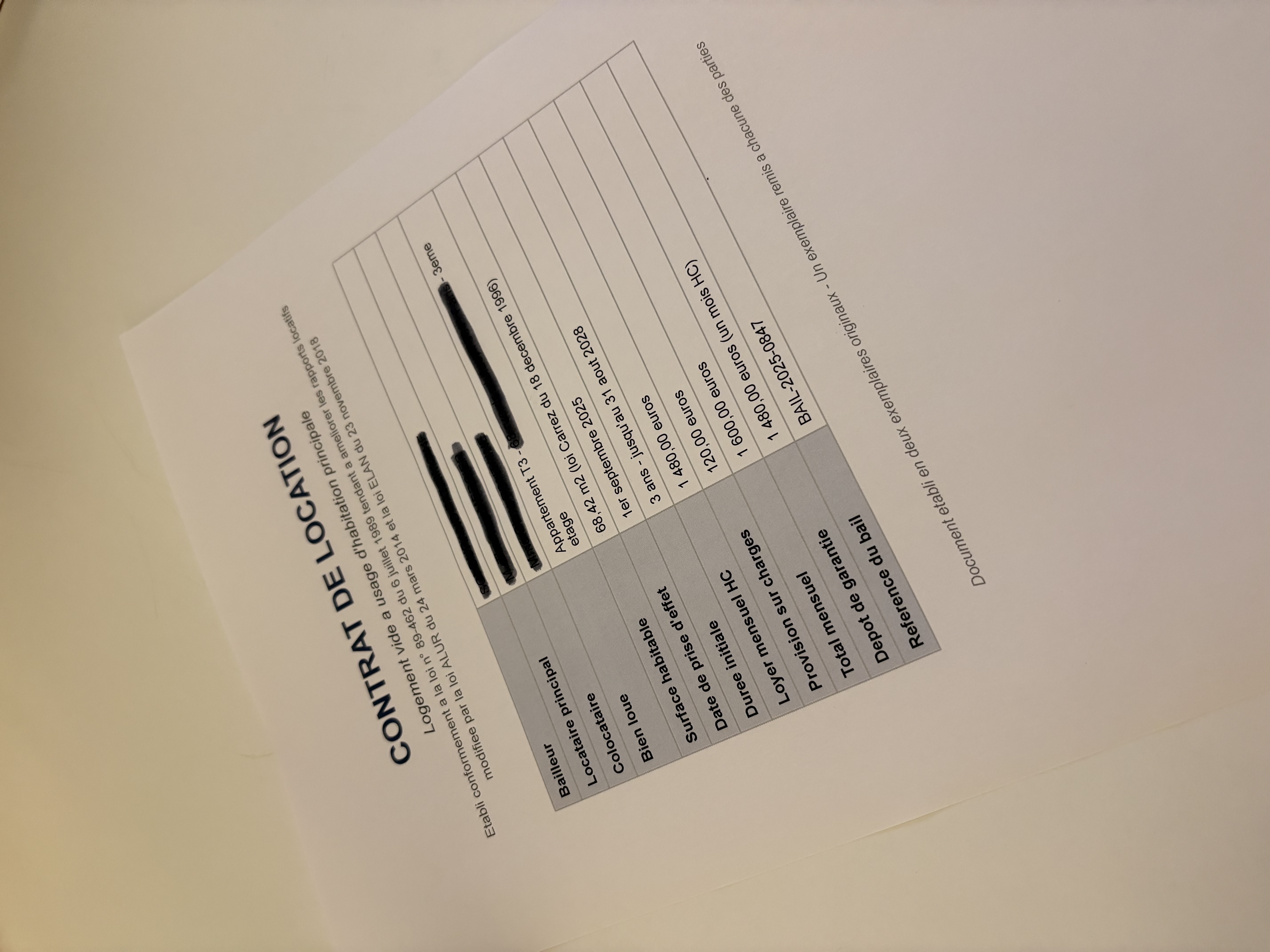 Première page d'un contrat de location imprimé, les noms du bailleur, du locataire et l'adresse barrés au feutre noir, les montants et les dates laissés lisibles.